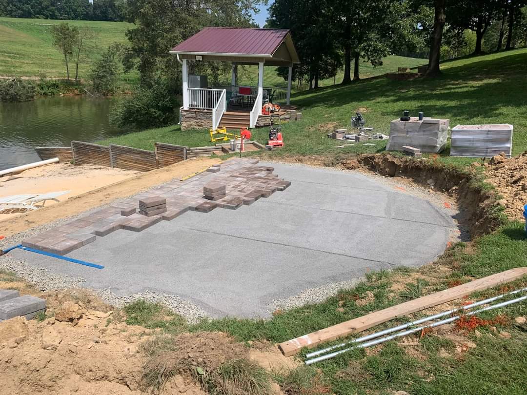 Paver patio installation in progress by lakeside gazebo